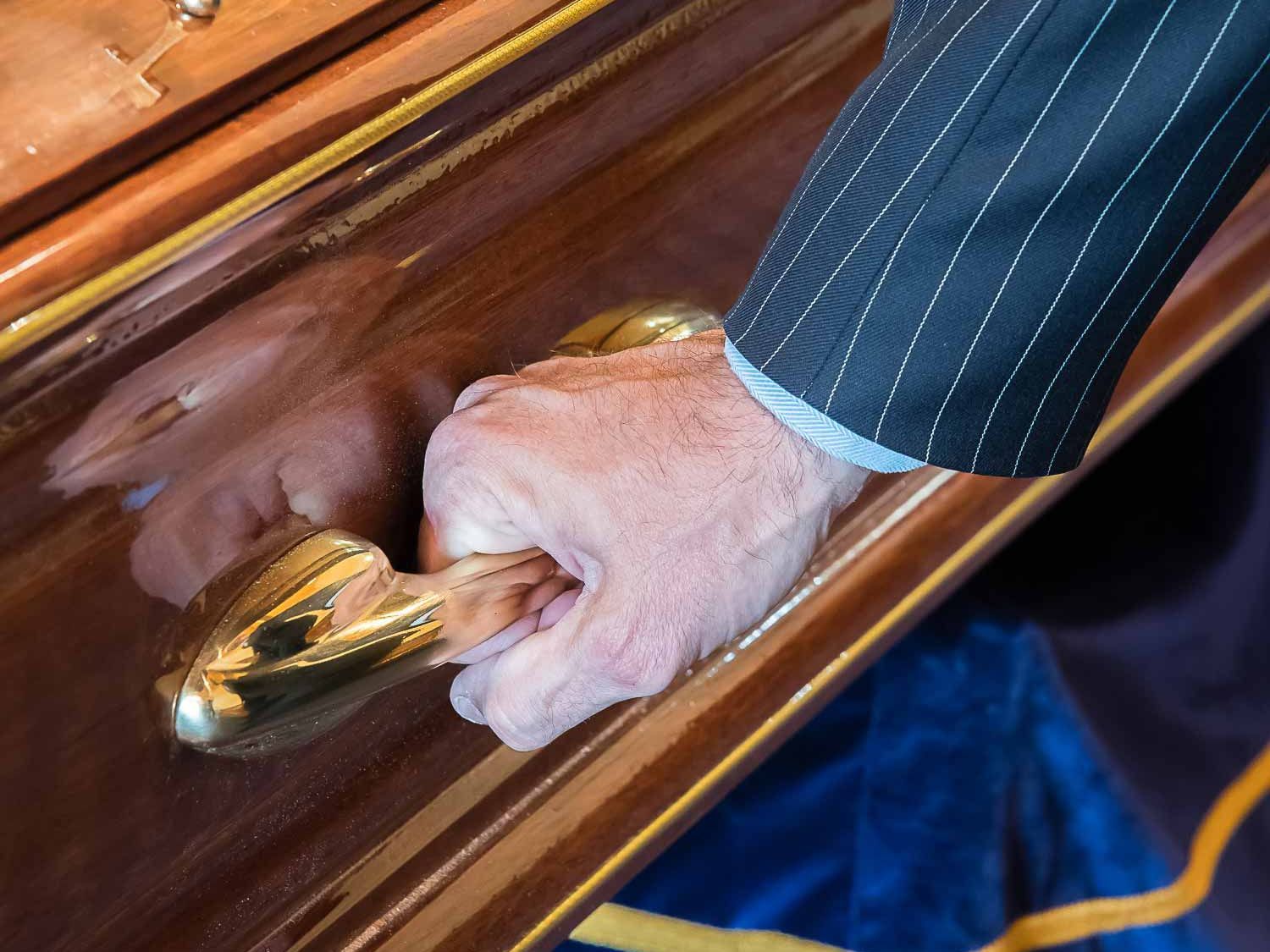 Holding the gold handle of a coffin